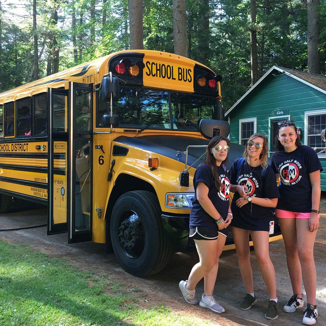 Camp Counselors standing by a yellow school bus